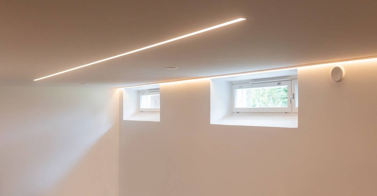Bande lumineuse LED le long du mur, derrière la moulure, et encastrée au centre du plafond.