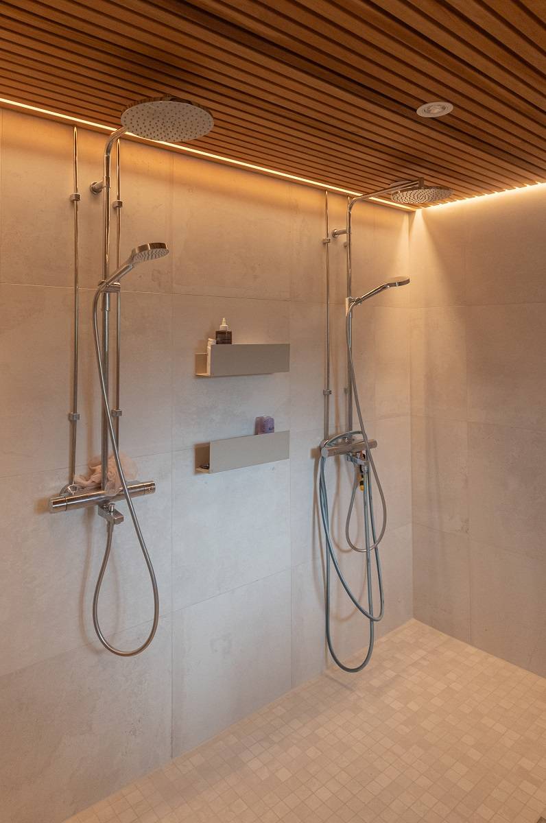 Dans la salle de bains, une bande LED est allumée au niveau de la corniche. De plus, un spot est fixé au plafond, mais il n'est pas allumé.