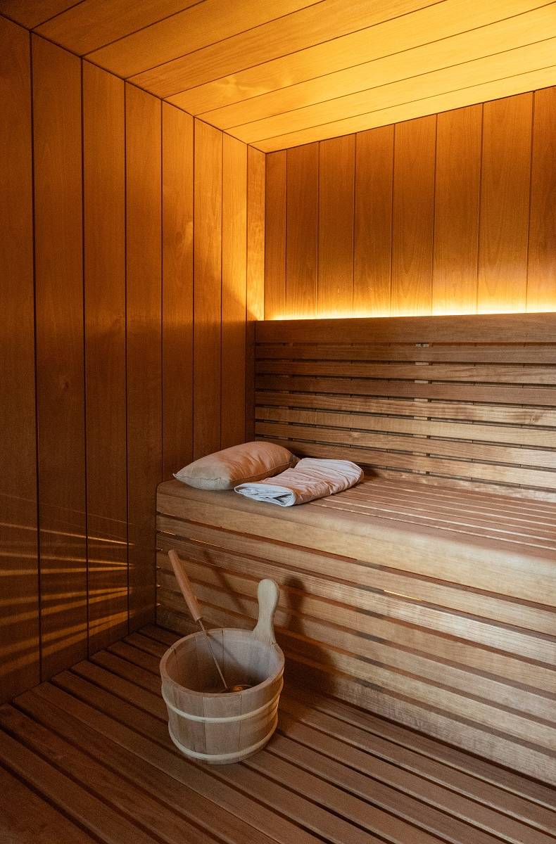 Derrière le dossier, une bande LED aux teintes chaudes éclaire directement vers le haut. De plus, sous les gradins, la lumière filtrant entre les lattes projette un motif lumineux sur le mur.