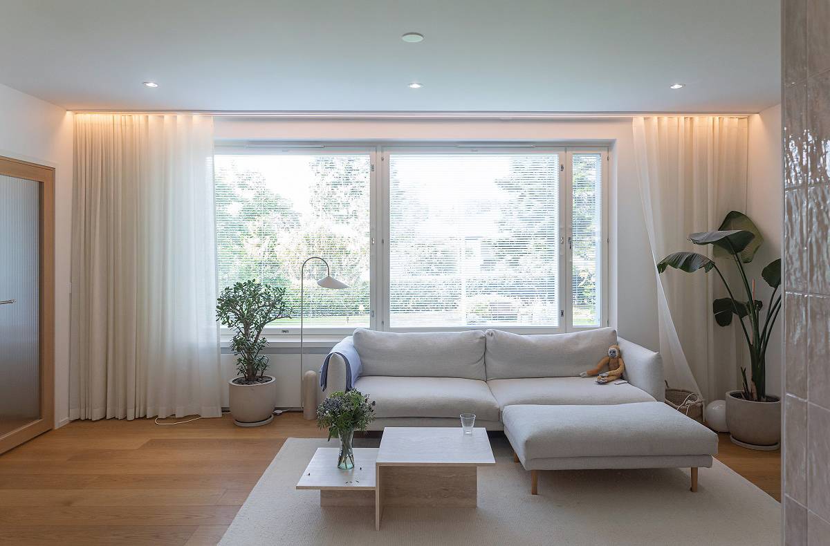 Derrière la tringle à rideaux du salon, une bande LED et des spots au plafond.