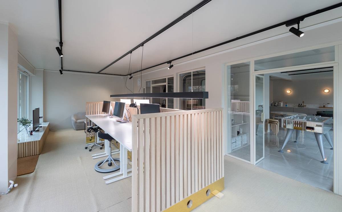 Bureau équipé d'un rail triphasé avec des spots au plafond et une lampe suspendue sur un long bureau.