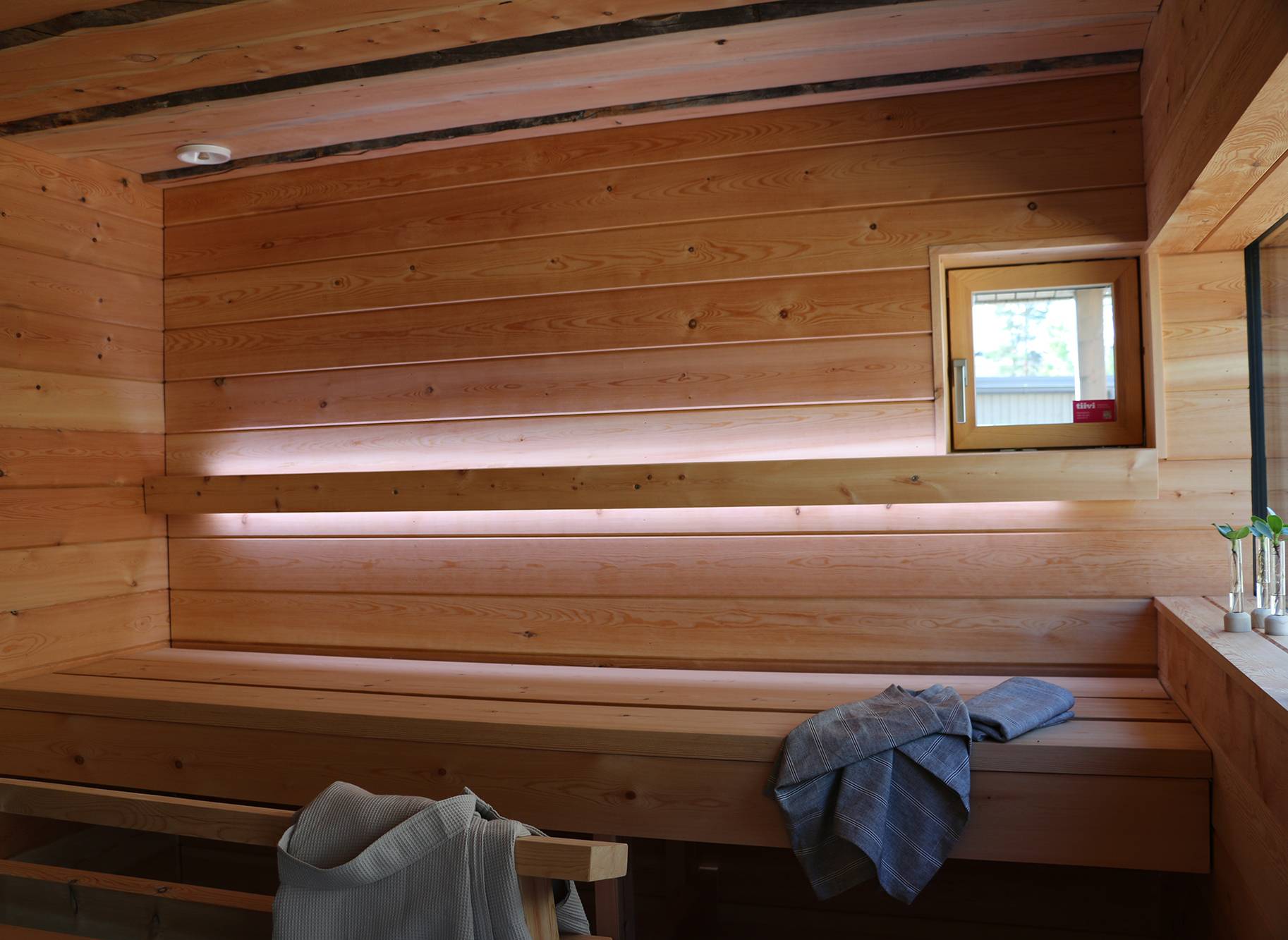 L\'éclairage du sauna est réalisé avec des bandes de LED sur le dossier. Les bandes LED éclairent vers le haut et vers le bas. Ledstore.fi