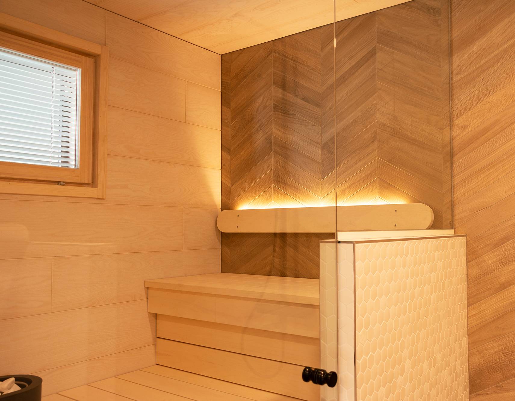 L\'éclairage du sauna a été réalisé avec une bande de LED sur le dossier orienté vers le haut. L\'éclairage des toilettes illumine également le sauna grâce aux parois en verre. Ledstore.fi
