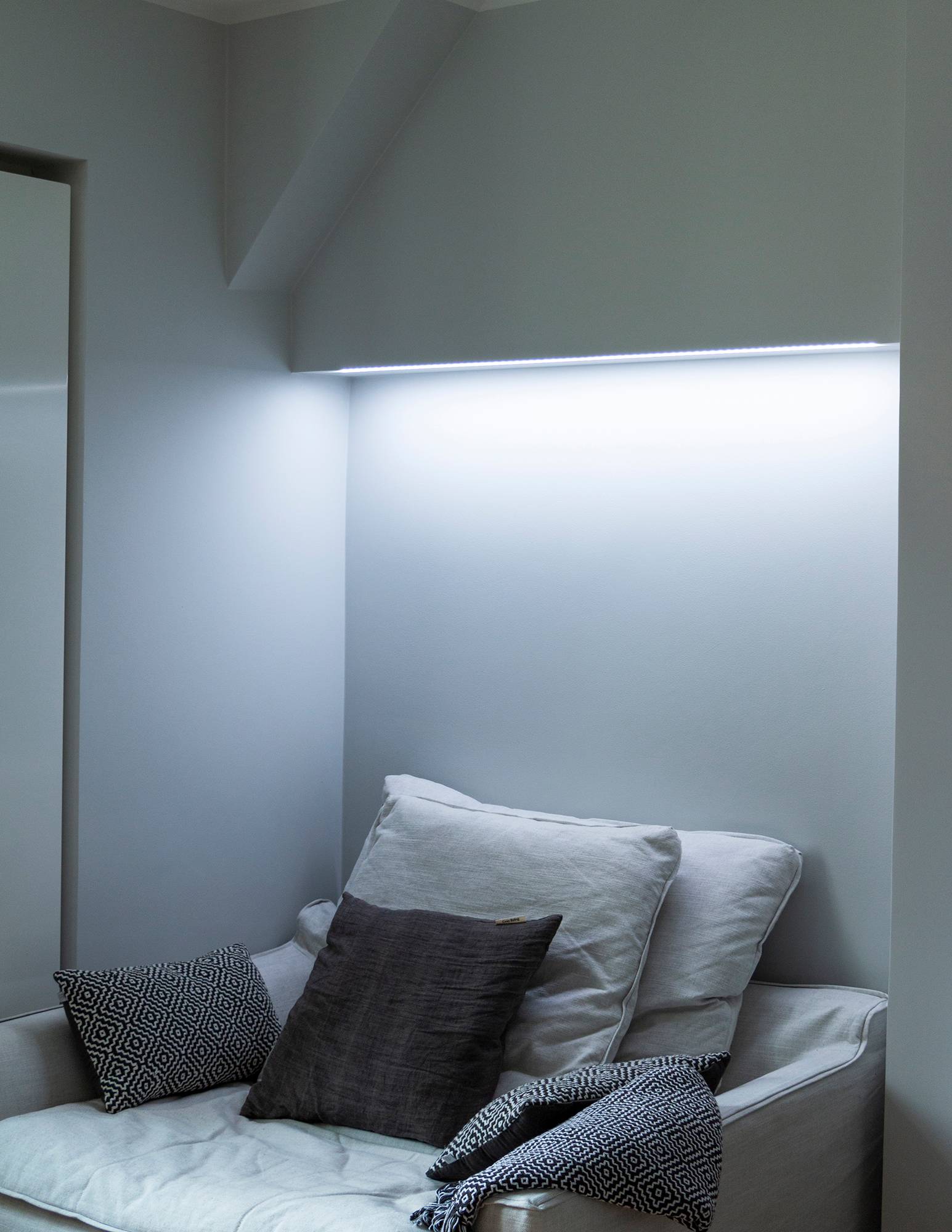 Chambre à coucher avec éclairage d\'ambiance à température de couleur réglable derrière le lit, monté sur la base de l\'armoire. Sur la photo, la température de couleur est réglée sur un ton froid. Ledstore.fi