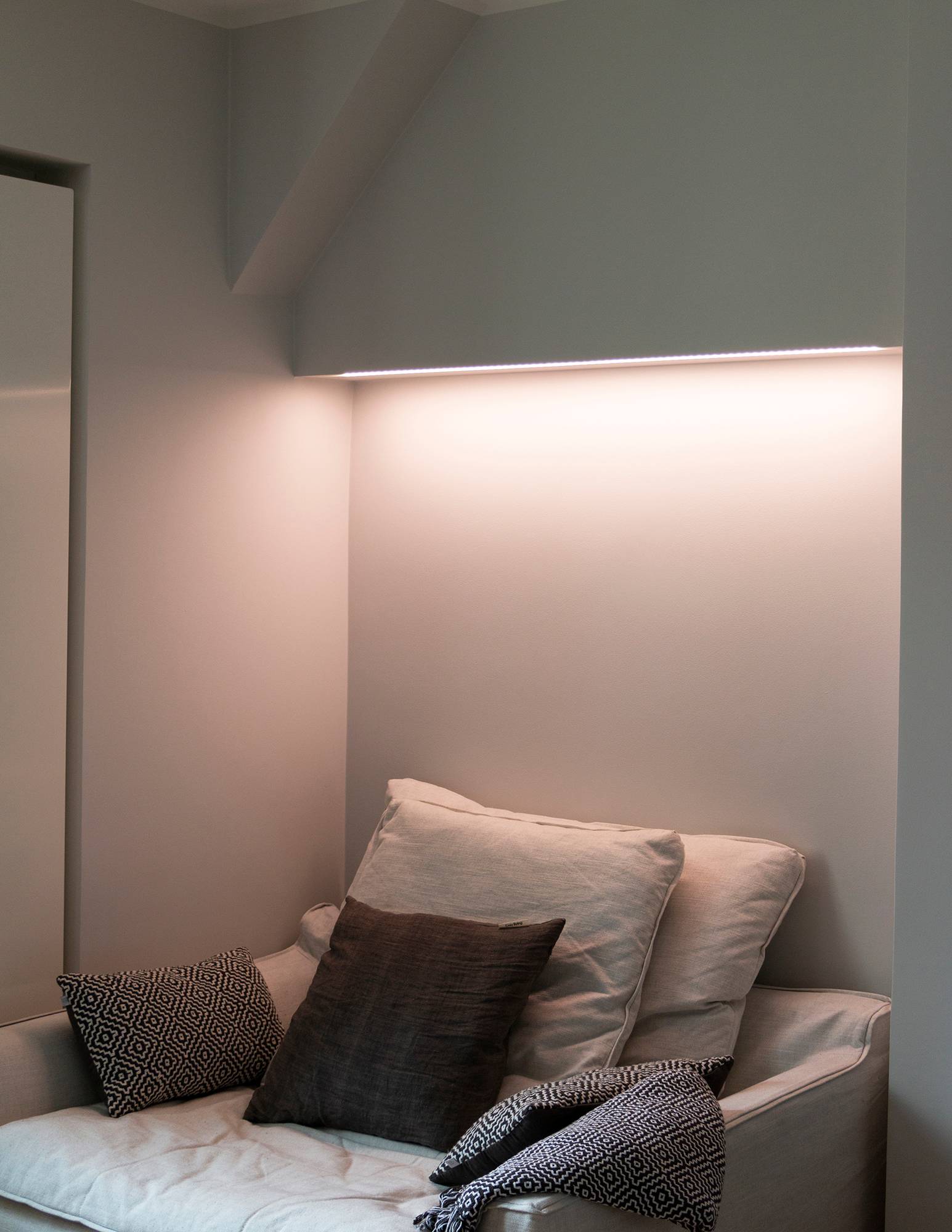 Chambre à coucher avec éclairage d\'ambiance contrôlé par la température de couleur derrière le lit, bande LED fixée au bas de l\'armoire dans une surface à profil bas. Ledstore.fi