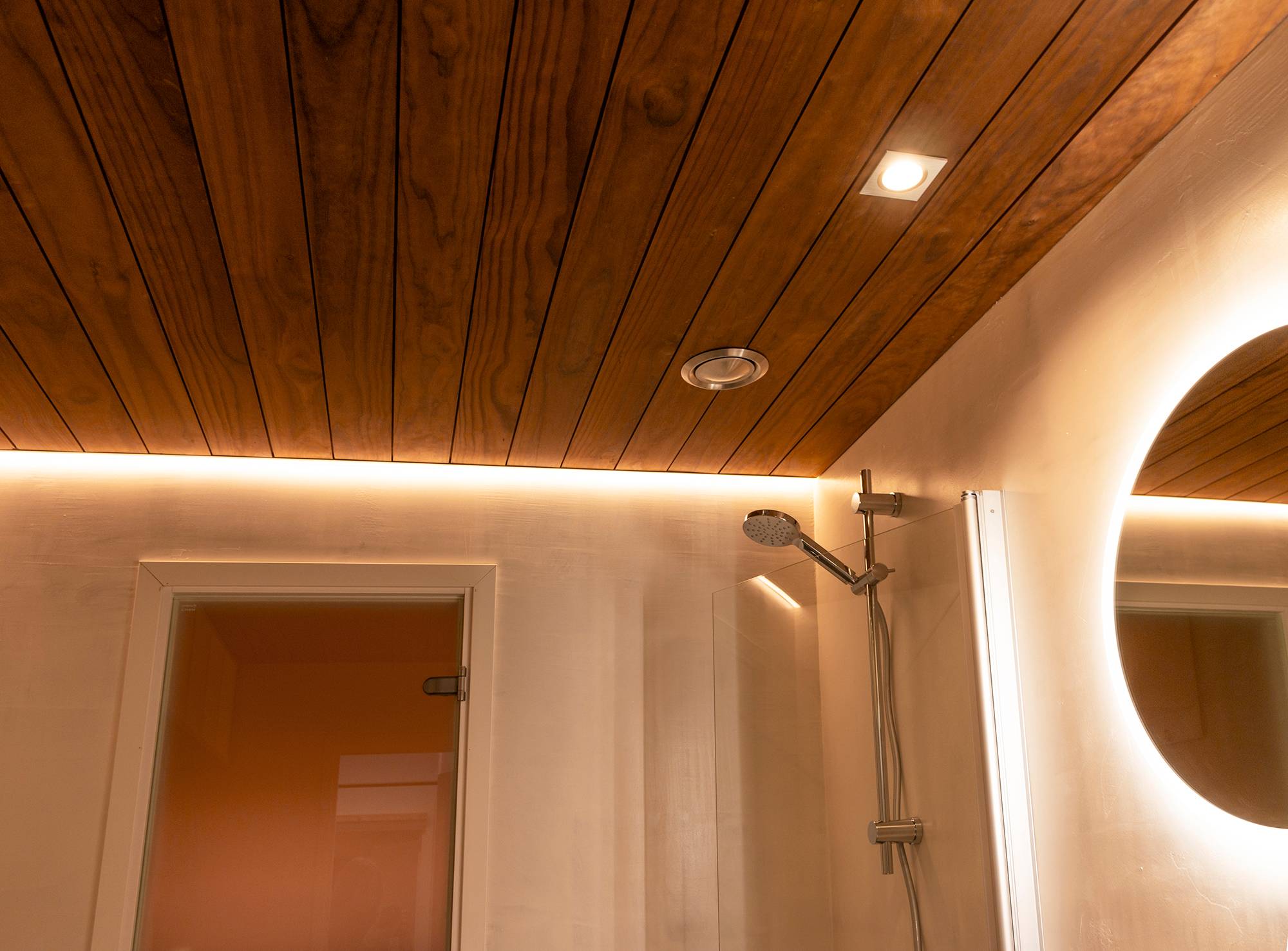 Profilé de bordure avec bande LED éclairant la douche combinée avec un miroir lumineux et des pots de plafond. Ledstore.fi