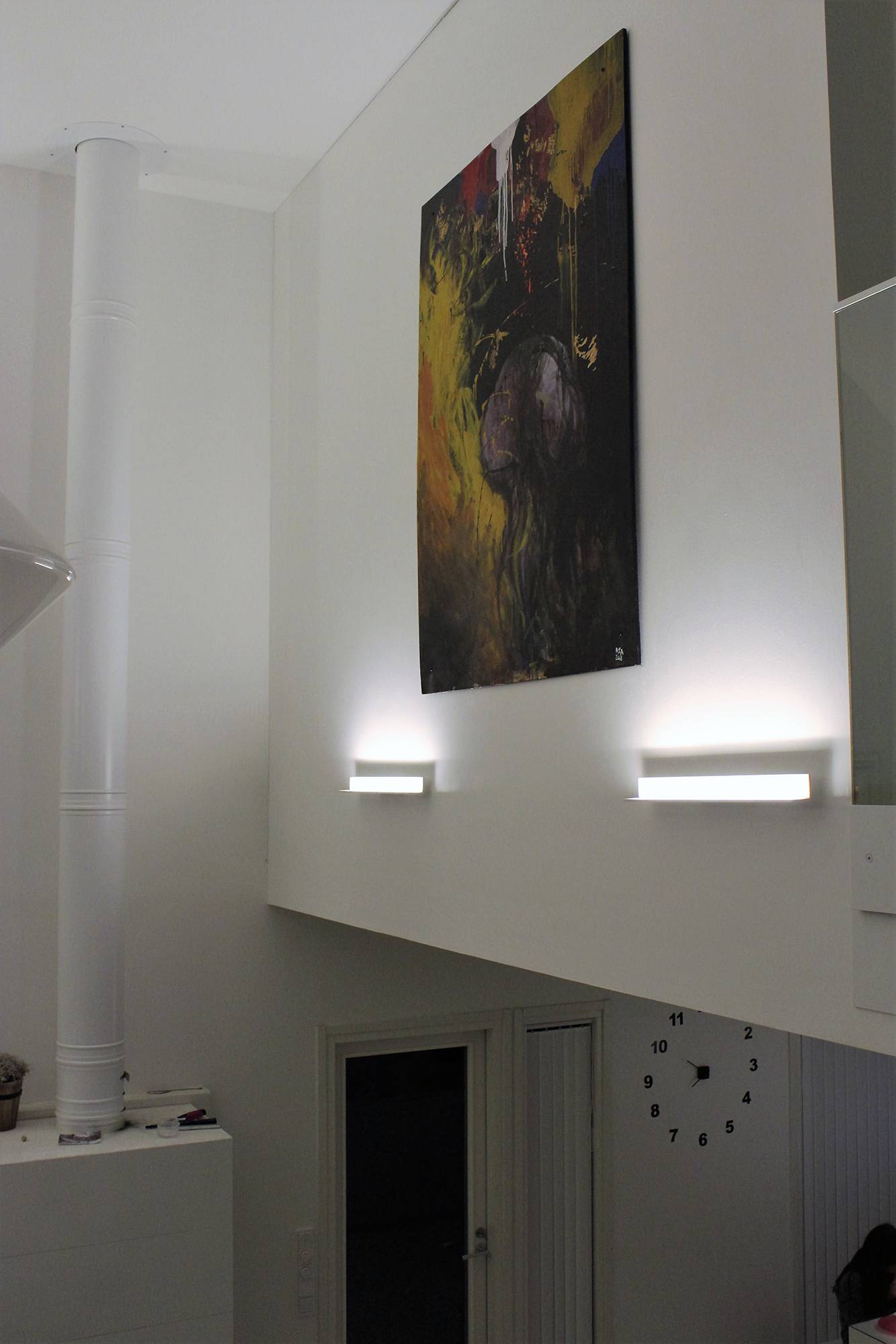 Appliques blanches BLADE mettant en valeur un tableau noir, orientées du bas vers le haut. Ledstore.fi