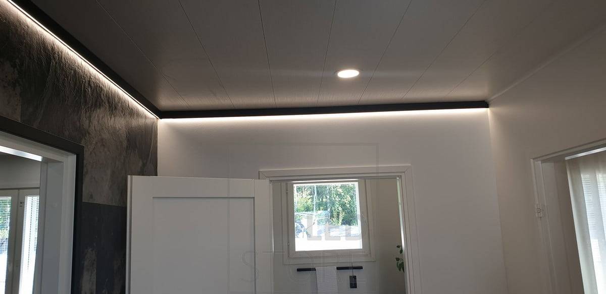 Un profilé mural noir décoratif avec une bande lumineuse LED fournissant une lumière indirecte. Ledstore.fi
