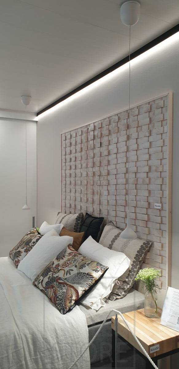 Derrière le lit, un profilé mural noir au plafond pour remplacer la moulure du plafond. Bande lumineuse à leds éclairant vers le bas une lumière indirecte à travers le mur. Ledstore.fi