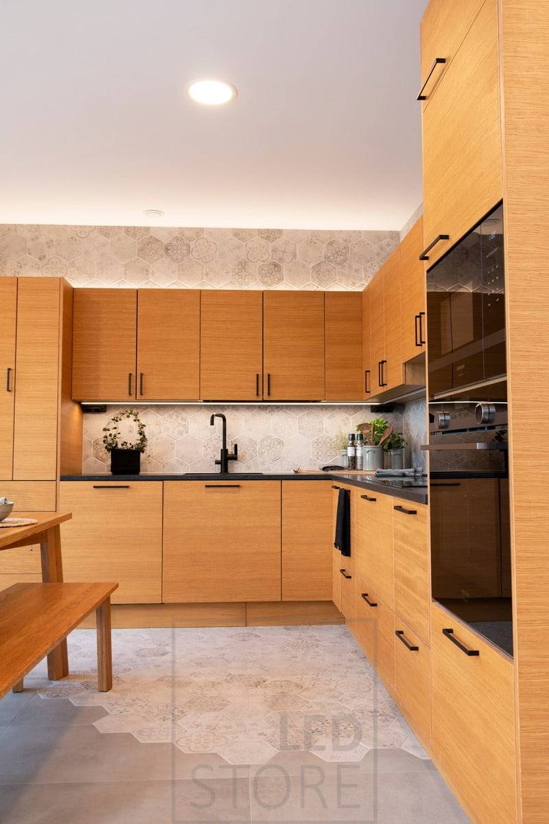 Dans la cuisine, éclairage indirect au-dessus des armoires, lumière douce et atmosphérique. Plafonniers encastrés pour l'éclairage général. Ledstore.fi