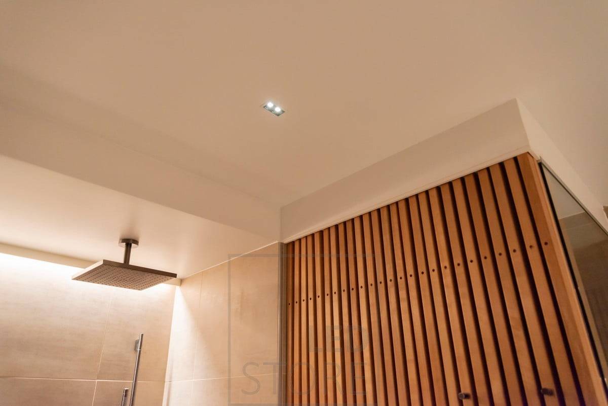 LINJA 2 au plafond de la salle de bain comme spot à angle étroit, derrière la douche comme éclairage d'ambiance avec une bande de LED éclairant une lumière indirecte. Ledstore.fi