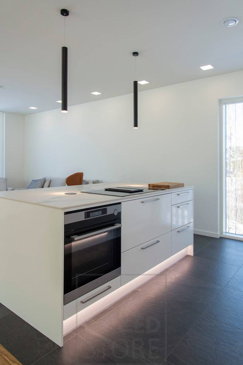 Un éclairage polyvalent crée une atmosphère agréable dans la cuisine ouverte. Le socle est éclairé par une bande LED pour la lumière indirecte et par une suspension PIPPU au sommet de l'îlot. Ledstore.fi