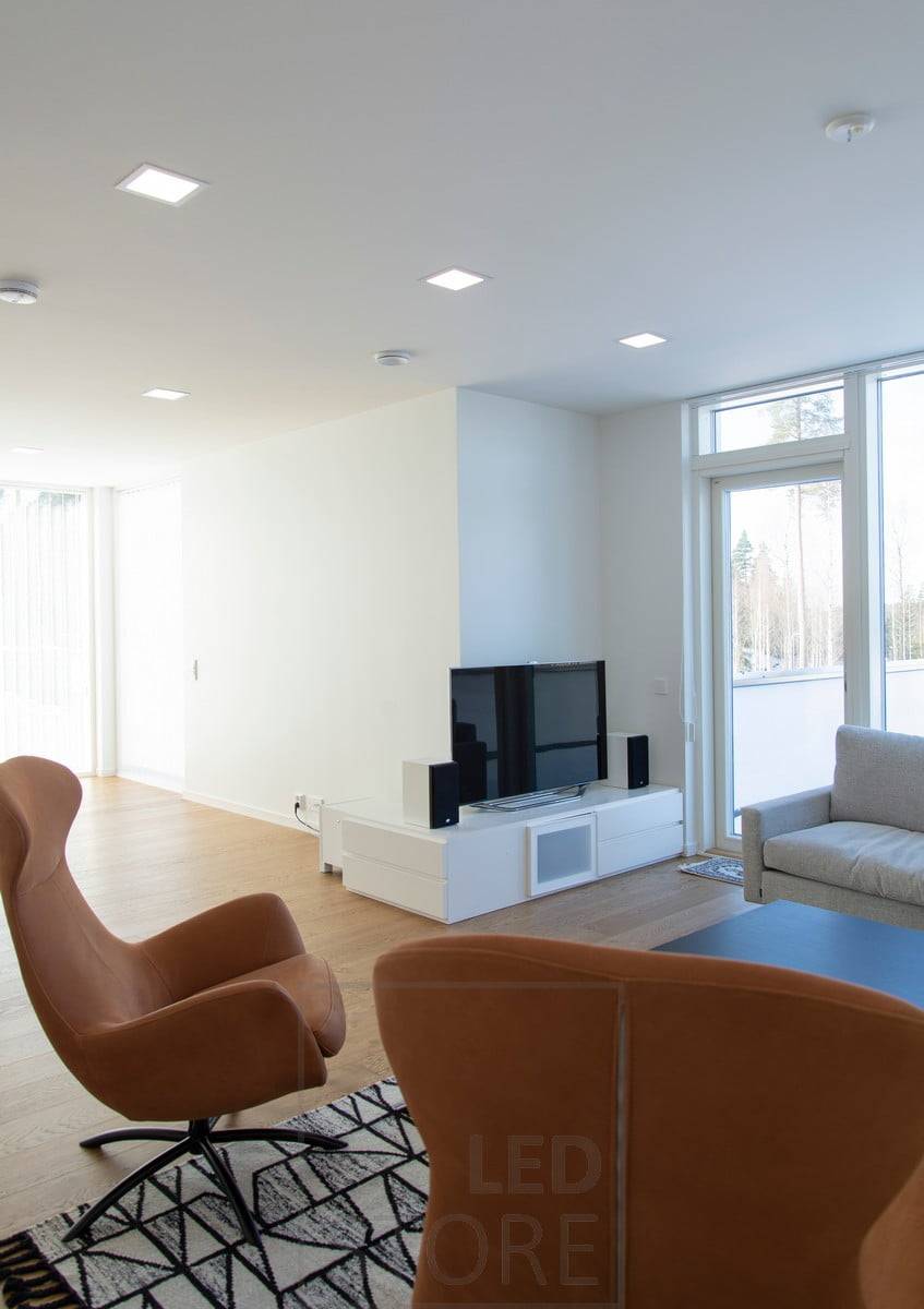 Des panneaux lumineux minimalistes s'intègrent parfaitement au plafond blanc et éclairent uniformément le salon. Le langage moderne du design s'accorde bien avec l'intérieur scandinave. Ledstore.fi