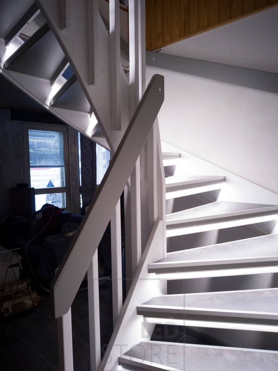 Des bandes LED sur les marches éclairent l'escalier d'une lumière indirecte. L'éclairage est doux et atmosphérique. Ledstore.fi