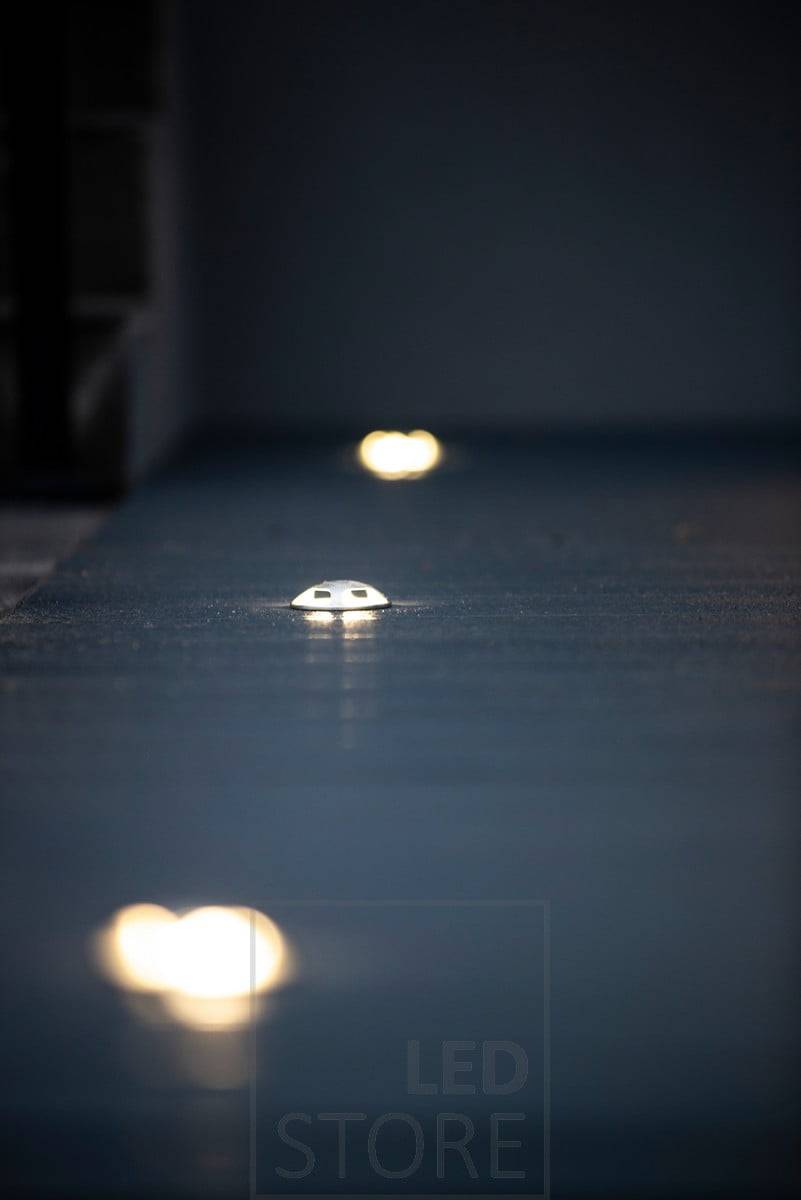 Projecteur de terrasse à quatre voies. Le corps est en acier inoxydable et le luminaire peut également être encastré dans le sol et le pavage, résistant à l'eau de mer et aux inondations. Ledstore.fi