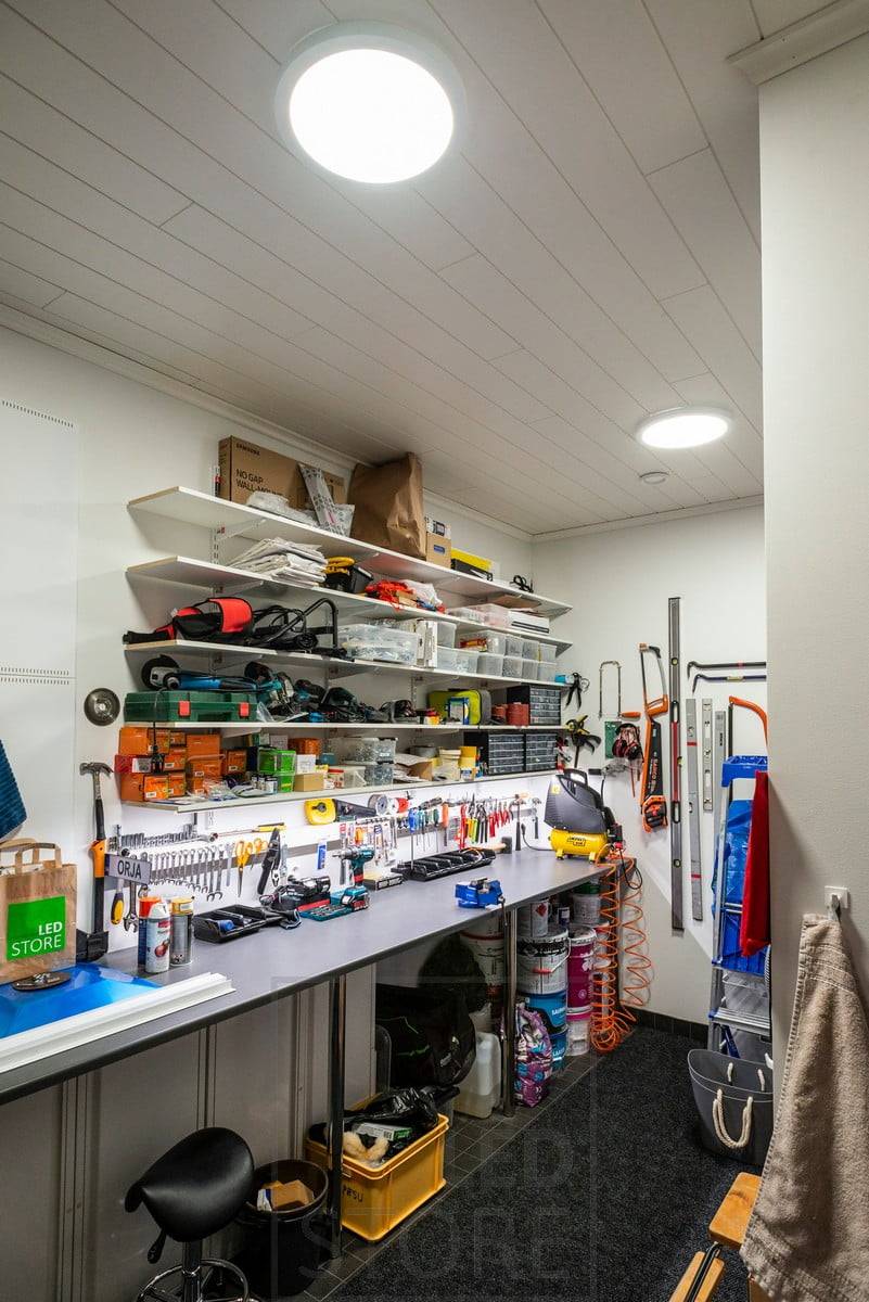 Poste de travail dans un entrepôt avec de grandes lampes suspendues au plafond. Ledstore.fi