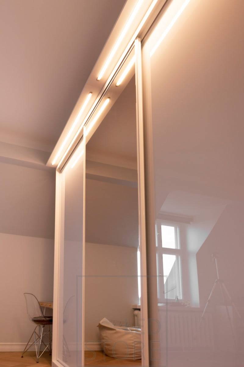 Une boîte construite sur le dessus d'une armoire avec une bande LED intégrée dans le profil affleurant. Il fonctionne comme une excellente lumière dans le couloir et éclaire l'armoire et son contenu. Ledstore.fi