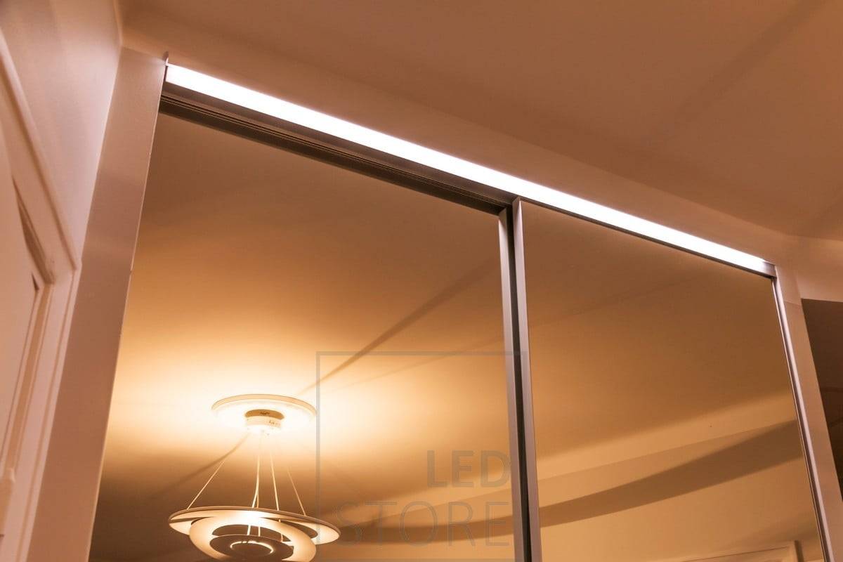 Cachée au-dessus du miroir d'une armoire, une bande LED éclaire l'armoire et son contenu d'une lumière indirecte. Ledstore.fi