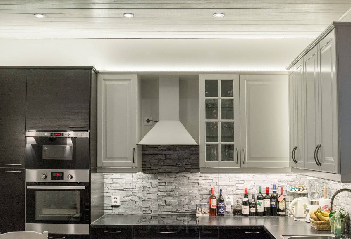 Eclairage du plan de travail de la cuisine combiné à des bandes LED sur le dessus des meubles et à des spots. Ledstore.fi