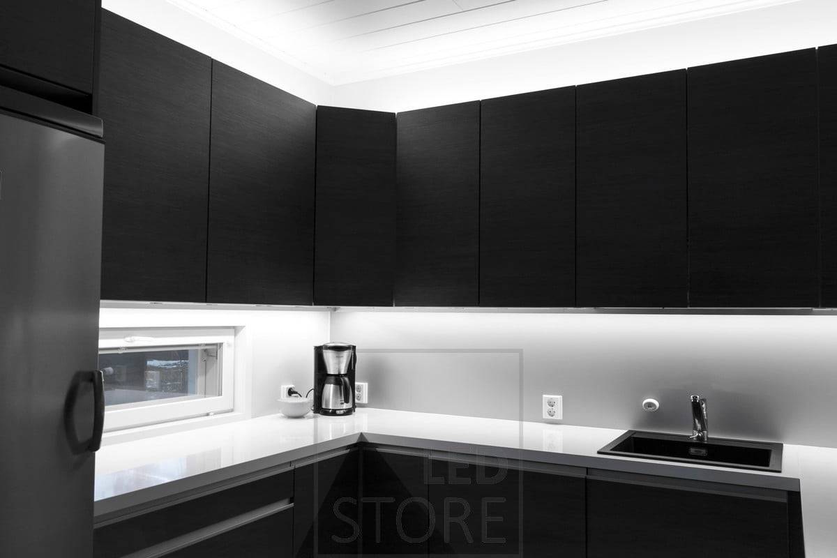 Eclairage de la cuisine avec des bandes de leds sur le dessus des armoires et attachées au bas des armoires pour apporter de la lumière au plan de travail. Ledstore.fi