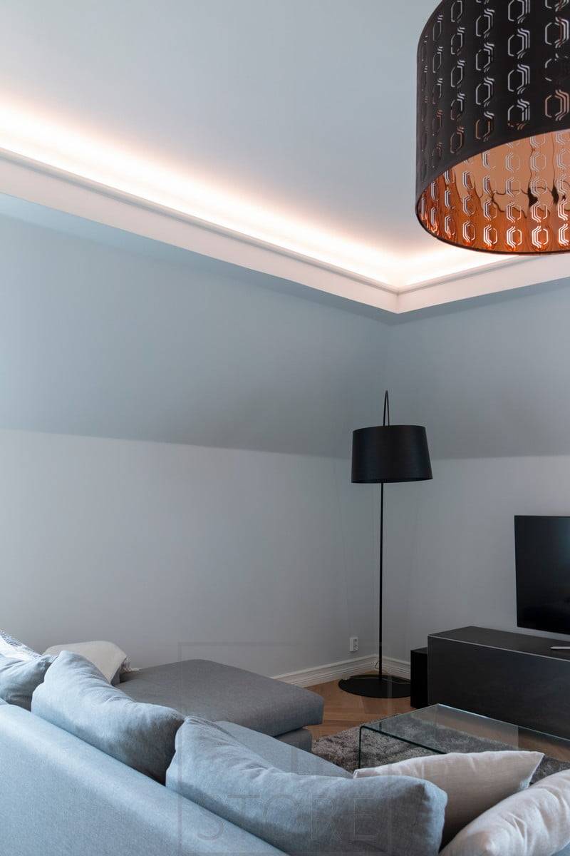 Au plafond d'une porte coulissante en verre abaissée, une bande LED éclaire indirectement le salon. Ledstore.fi