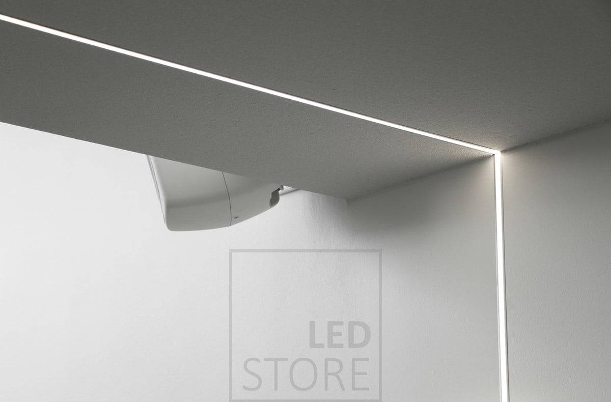 Bande LED montée sur un profilé encastré, s'étendant du plafond au mur. Ledstore.fi