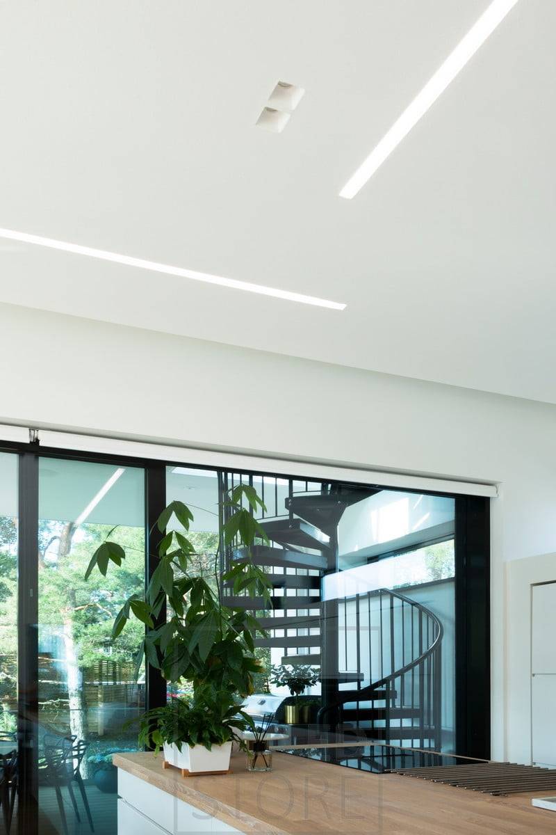 Un large profilé affleurant combiné à des spots pour créer un éclairage général dans une grande salle de séjour ouverte. Ledstore.fi