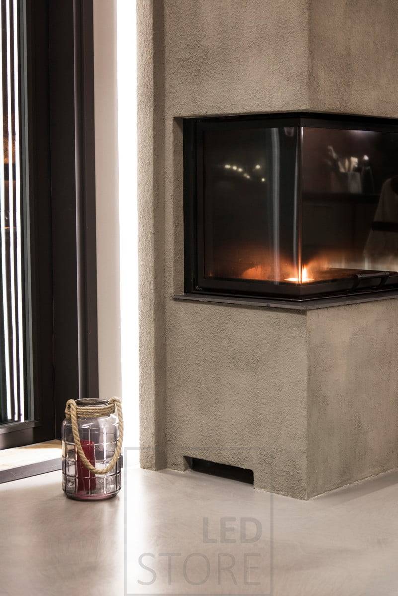 Dans le salon, derrière la cheminée, une bande LED fournit un éclairage d'ambiance indirect et doux à travers le mur. Ledstore.fi