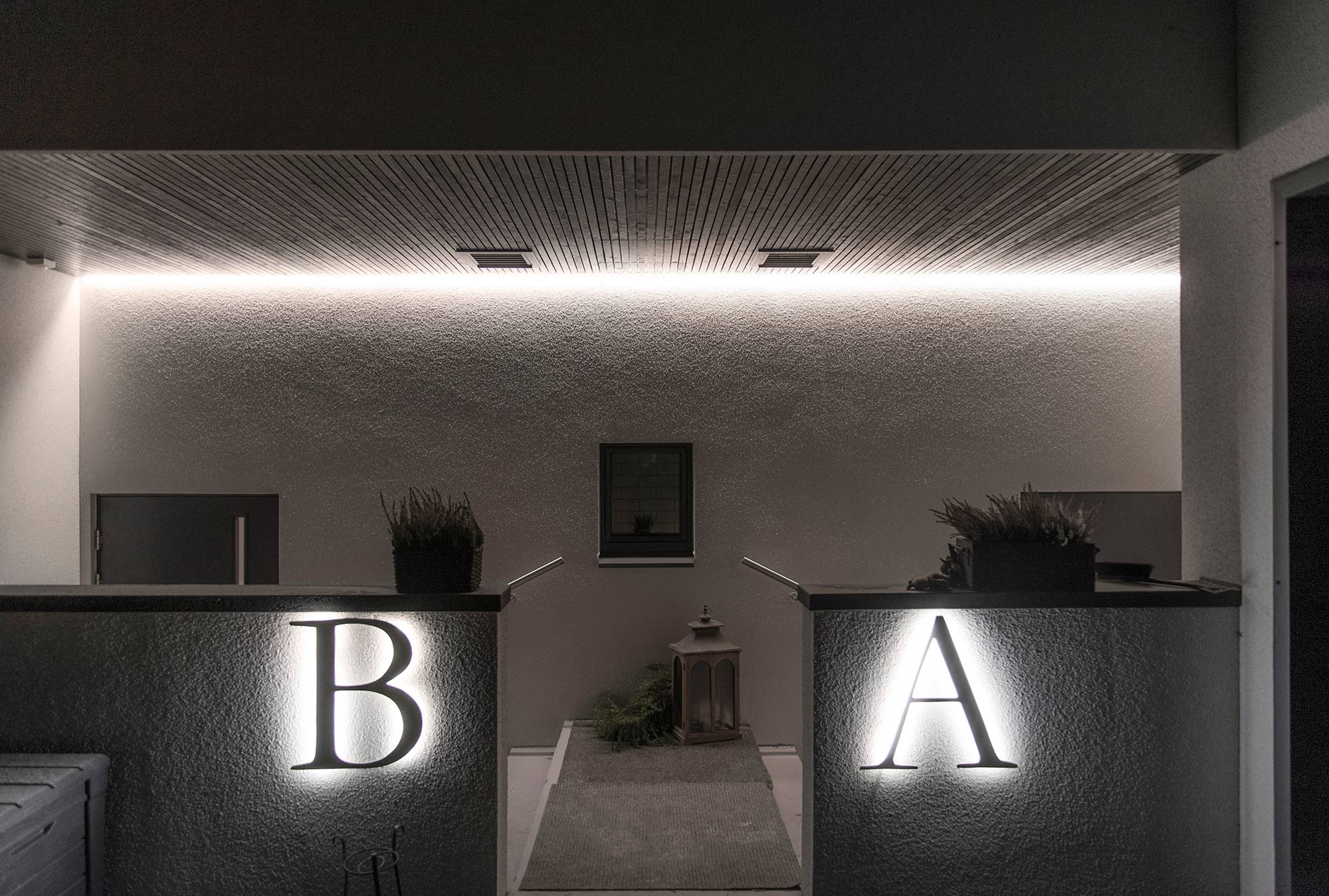 Les lettres extérieures des maisons éclairées par des bandes LED et l\'entrée éclairée par une bande LED à éclairage indirect. Ledstore.fi