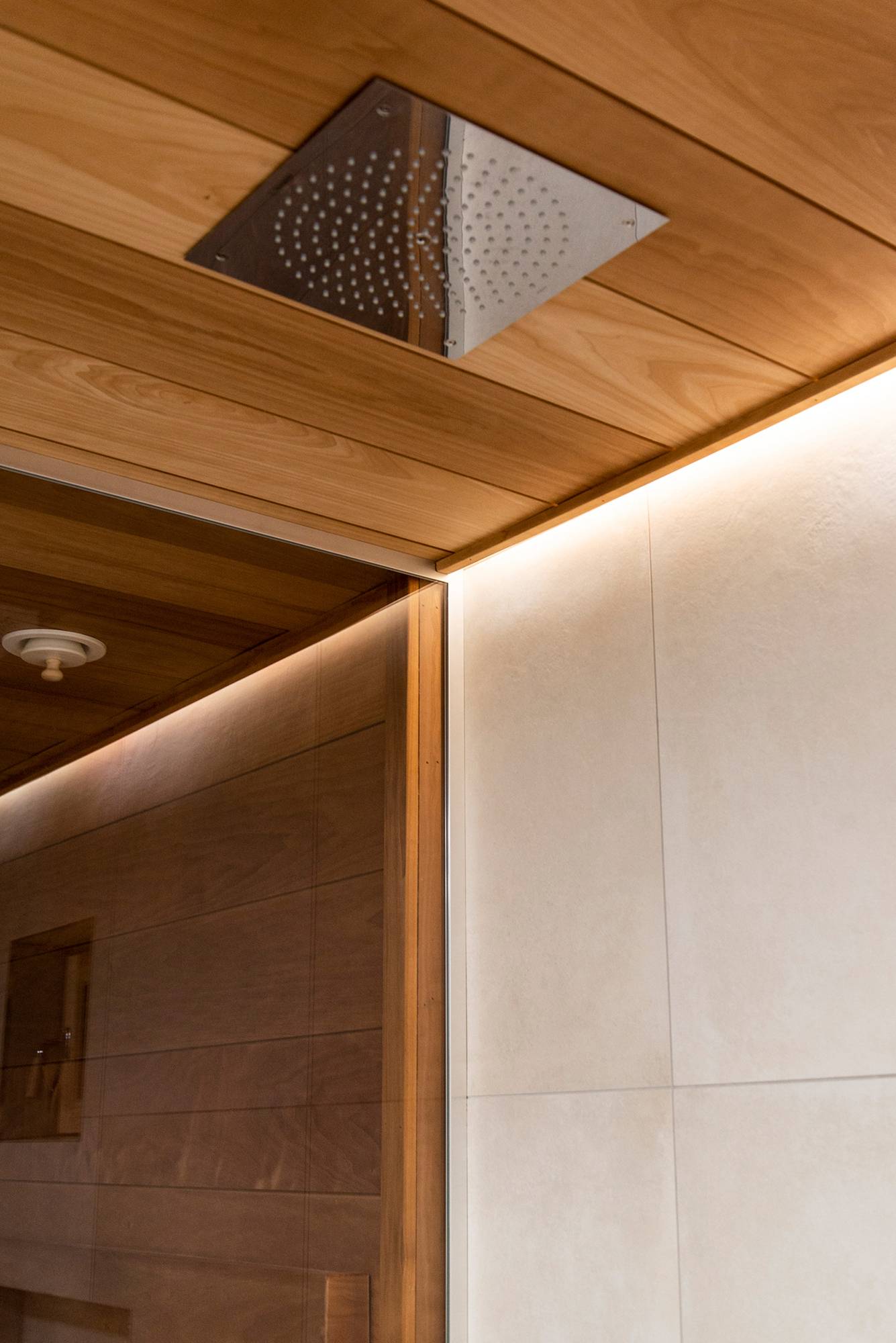 Une bande de LED derrière la pomme de douche pour éclairer la salle de bains avec une lumière atmosphérique et indirecte. Ledstore.fi