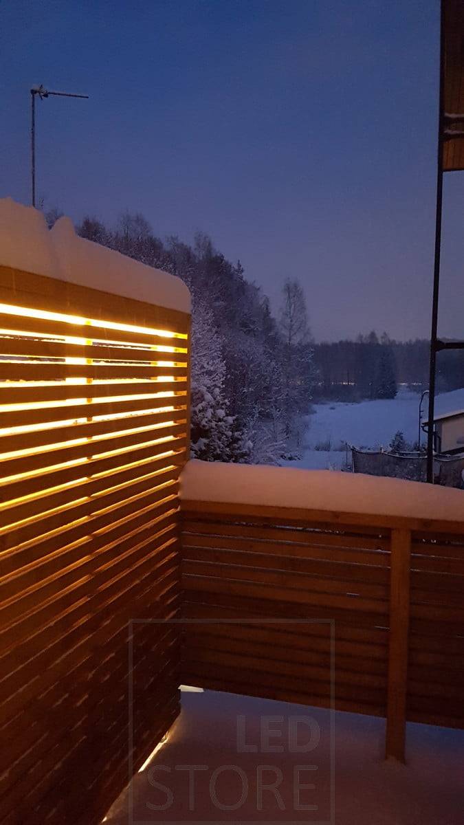 Eclairage d'ambiance dans la cour, une bande de leds à l'intérieur de la clôture éclaire indirectement la cour. Ledstore.fi