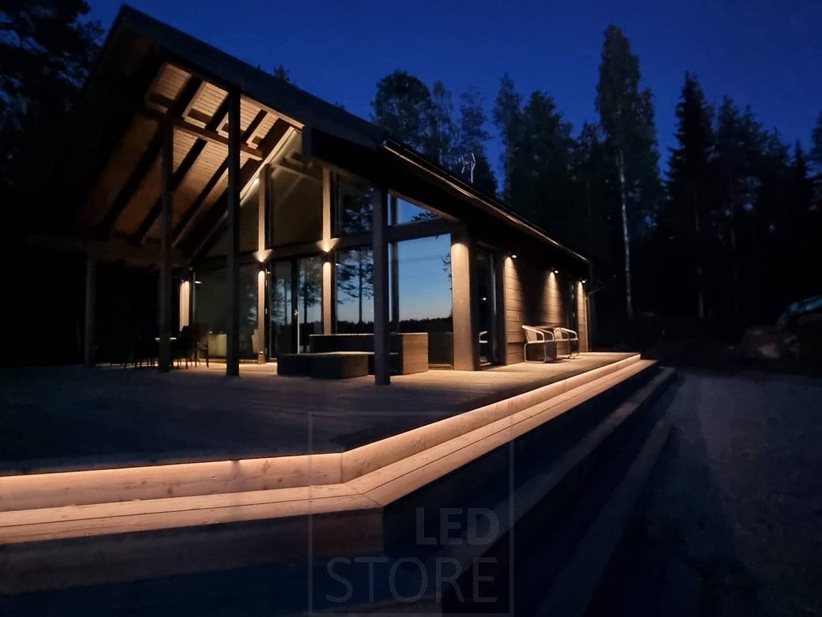 Eclairage extérieur polyvalent et atmosphérique avec une bande LED sur l'escalier et des appliques murales. Les appliques murales éclairent dans deux directions au point haut et dans une direction au point bas. Ledstore.fi