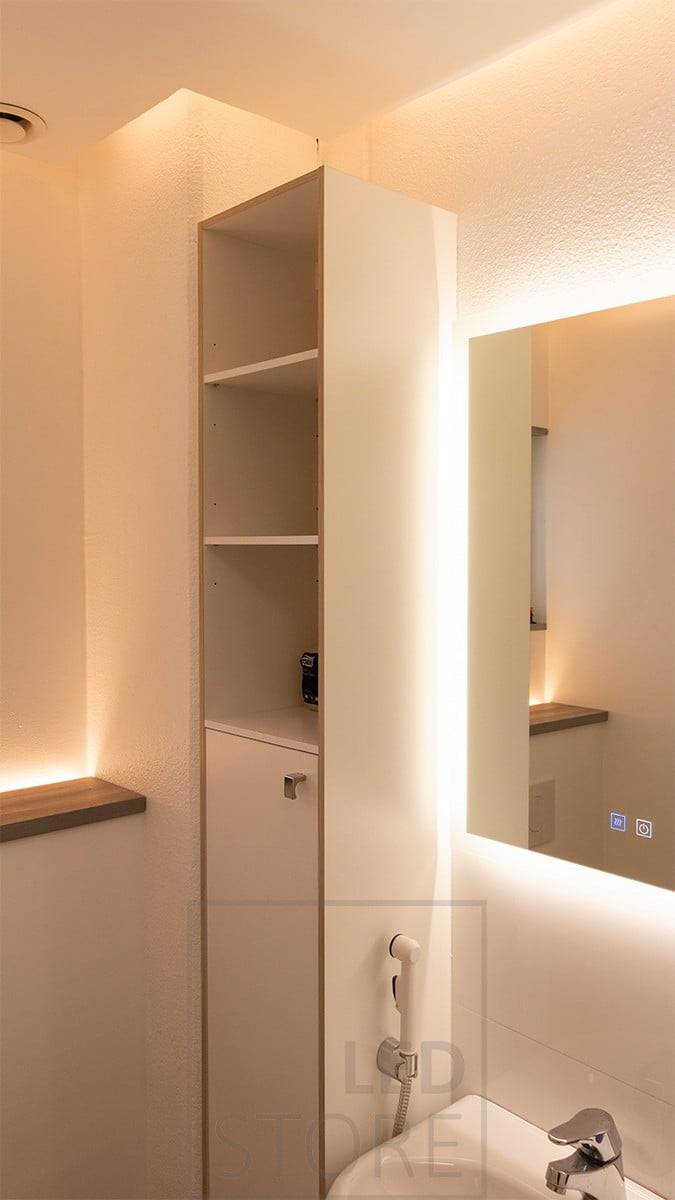 Une cabine de toilettes murale avec une bande LED orientée vers le haut. Créant une lumière d'ambiance dans l'espace, elle s'allume grâce à un détecteur de mouvement et peut donc également servir de veilleuse. Dans le plafonnier, la bande de LED est dirigée vers le mur. Avec l'ajout d'un miroir lumineux, l'ensemble des toilettes est éclairé indirectement. Ledstore.fi