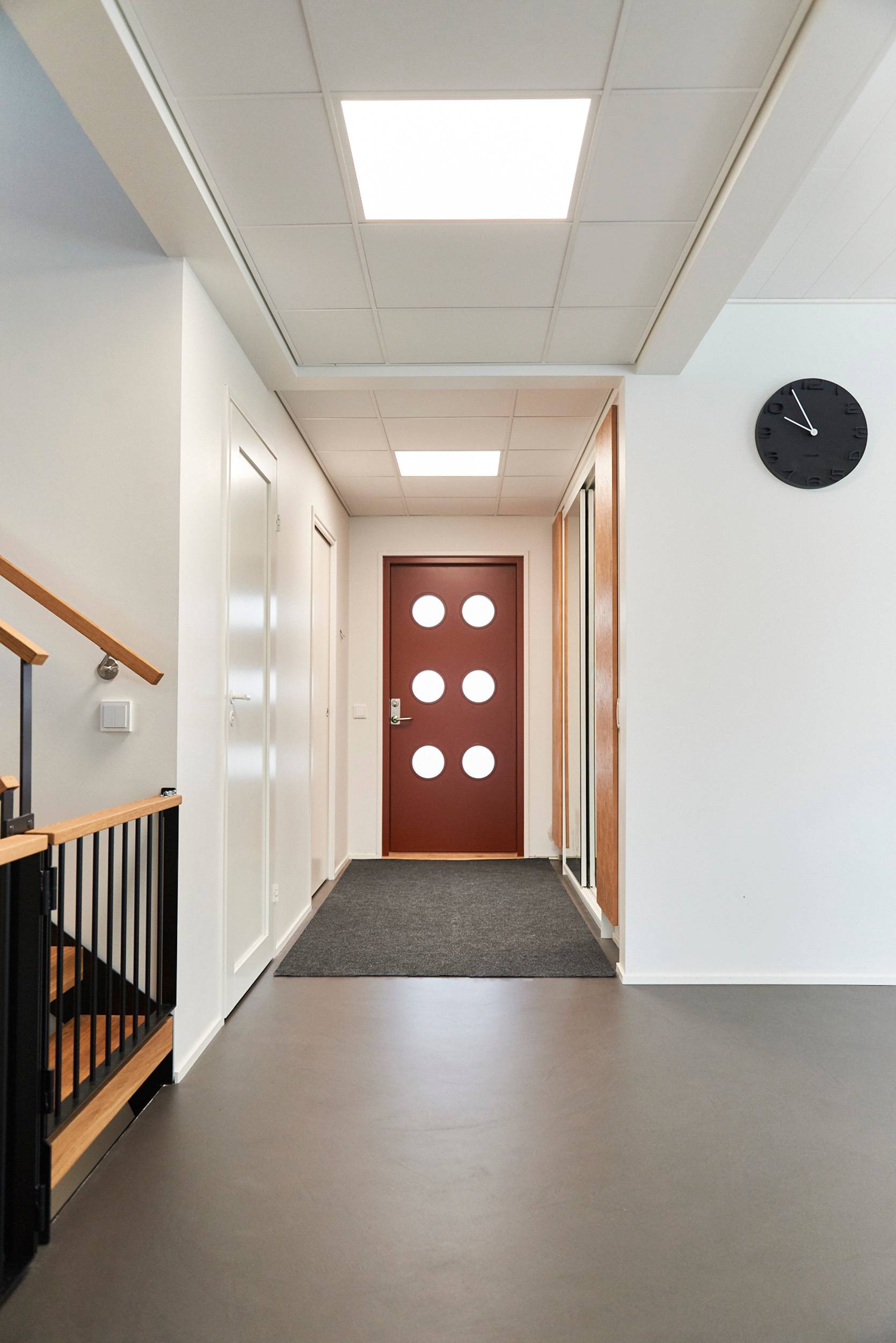 De grandes lampes à panneaux ressemblant à des puits de lumière sont installées au plafond du hall d\'entrée. Les lampes éclairent l\'espace de manière uniforme et efficace. Les luminaires sont gradables et, si on le souhaite, peuvent également être gradés en termes de température de couleur. Ledstore.fi