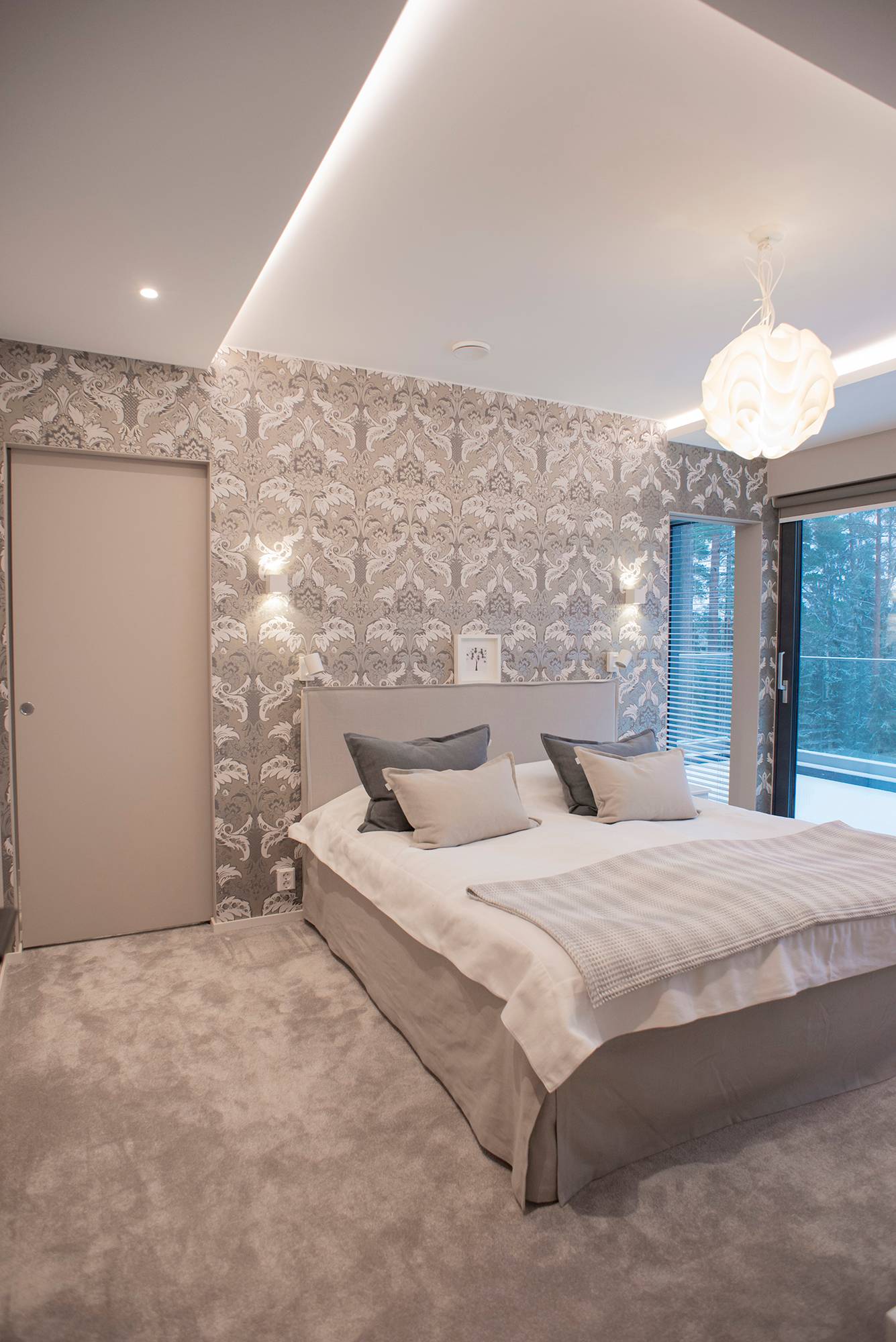 Une chambre à coucher avec un éclairage polyvalent et digne d\'un hôtel. Éclairage indirect autour de la pièce, éclairage ponctuel et suspension décorative au centre de la pièce. Appliques murales de part et d\'autre du lit. Ledstore.fi