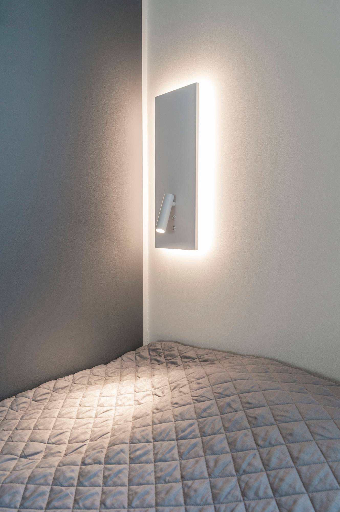 Applique NIGHT en blanc. Avec un éclairage d\'ambiance indirect et doux en arrière-plan et une lampe de lecture directionnelle qui s\'allume à l\'aide d\'un interrupteur séparé. Ledstore.fi