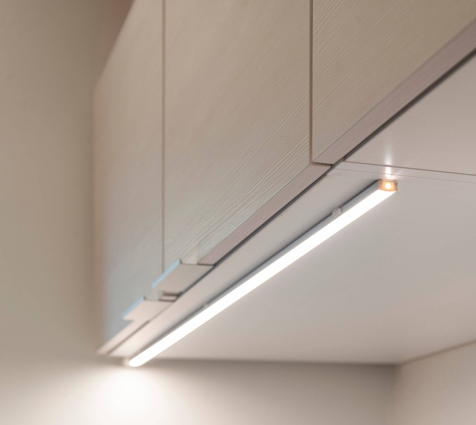 Profilé LED monté sur le bord avant d\'une armoire, introduit dans le plan de travail. Ledstore.fi