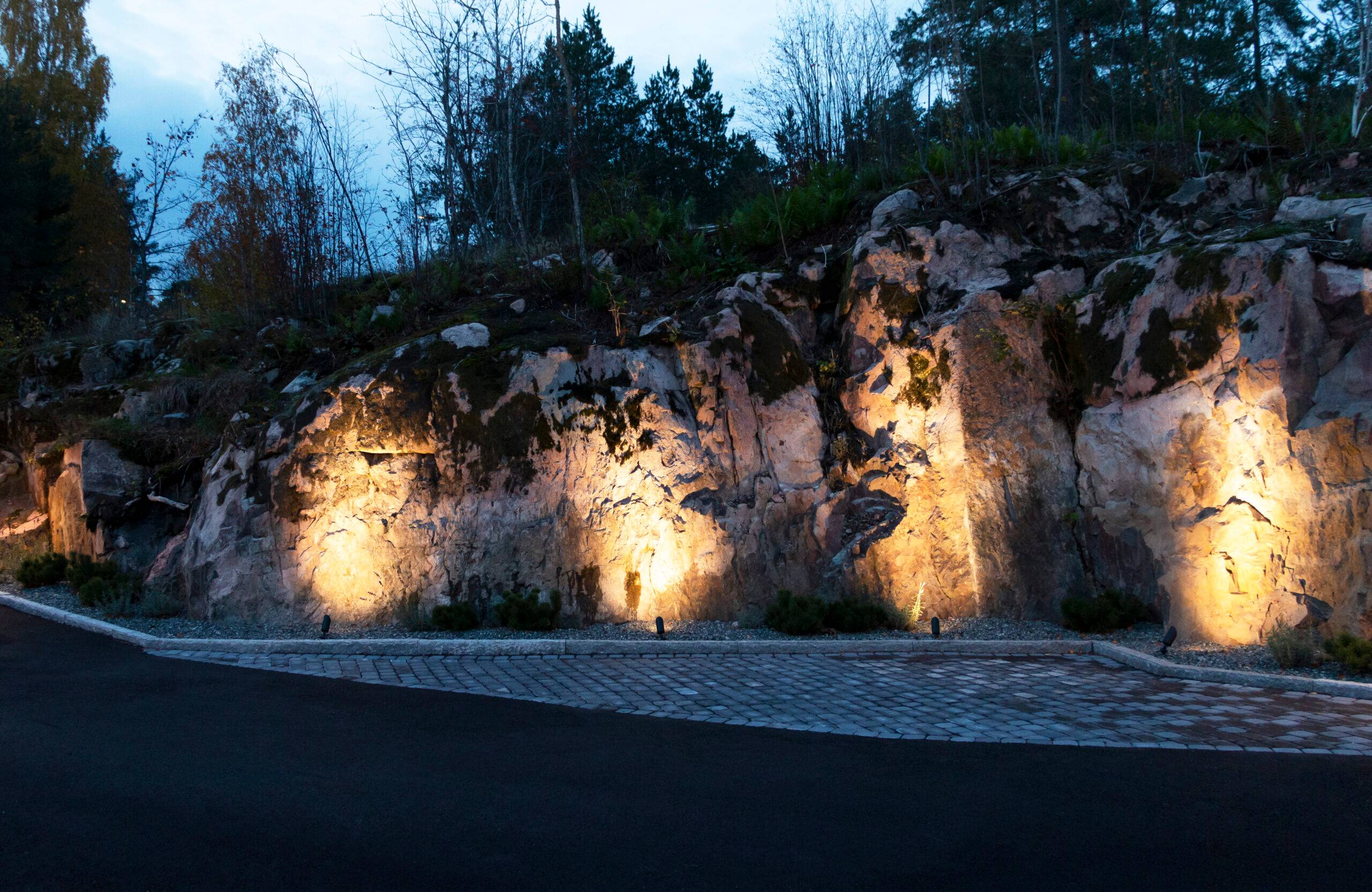 Au bord de la cour rocheuse, des éclairages paysagers à LED accentuent les formes rigides.