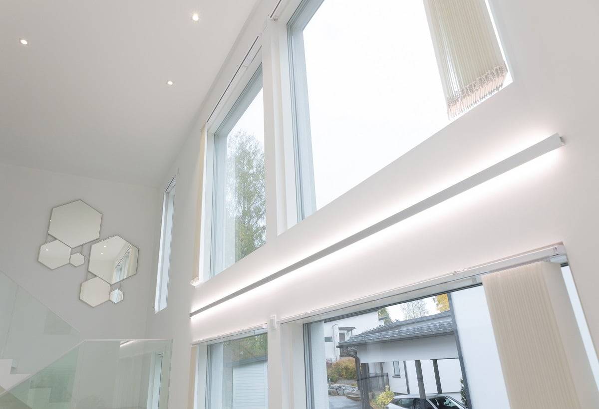 LedStore.fi online store description du produit : l'intérieur moderne se caractérise par de grandes et hautes fenêtres étonnantes, dotées d'un éclairage LED élégant. Cet éclairage permet à la lumière naturelle de pénétrer à l'intérieur. Sur les murs blancs, on trouve un ensemble de miroirs hexagonaux artistiquement disposés près de l'escalier avec une balustrade en verre. À l'extérieur, l'allée est bordée de voitures garées, ce qui complète le style moderne.