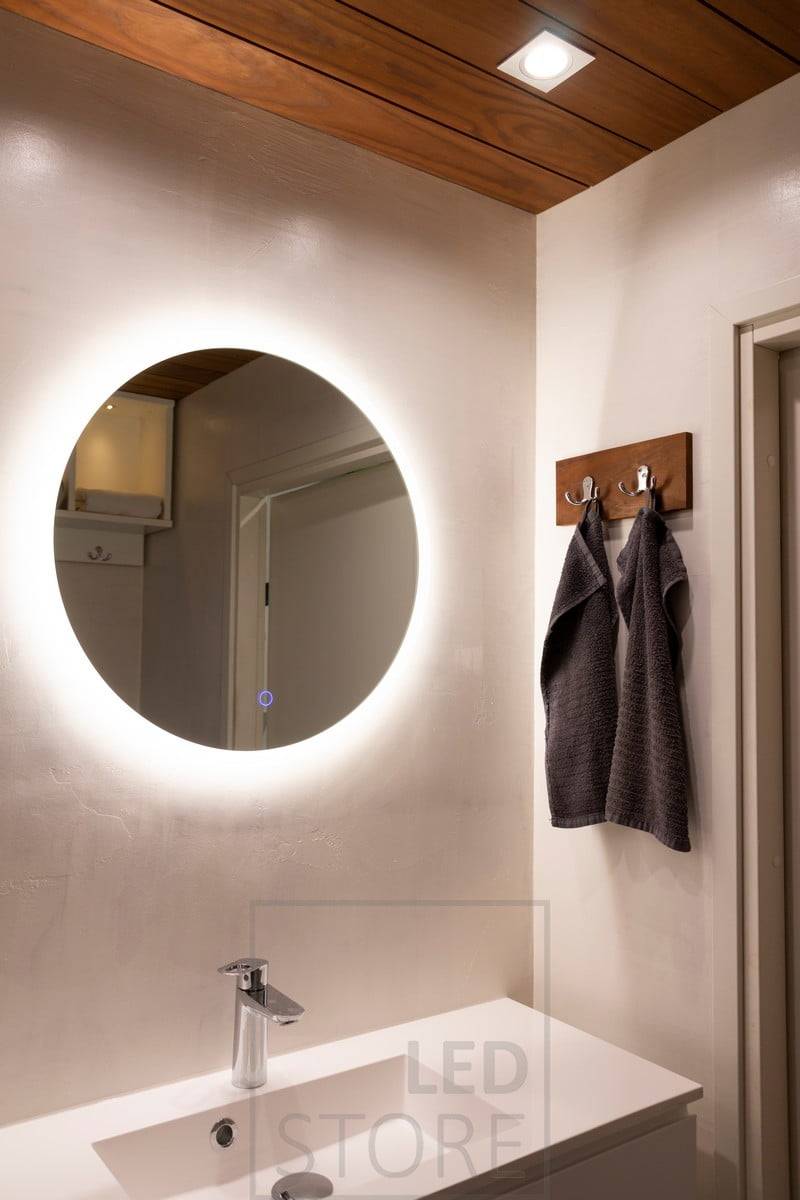 Le petit miroir lumineux MOON, d'un diamètre de 600 mm, est idéal pour les salles de bains et les toilettes afin d'ajouter une atmosphère et un éclairage supplémentaire (IP55). Le spot KANTTI situé au-dessus du miroir éclaire directement le visage.  Ledstore.fi