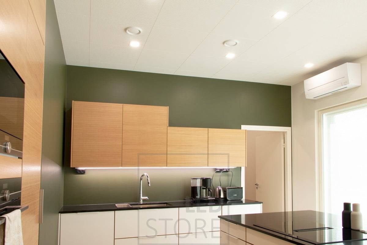 Éclairage plat au plafond dans la cuisine avec des panneaux LED carrés et une bande lumineuse LED au bas des armoires supérieures en guise d'éclairage plat. Ledstore.fi