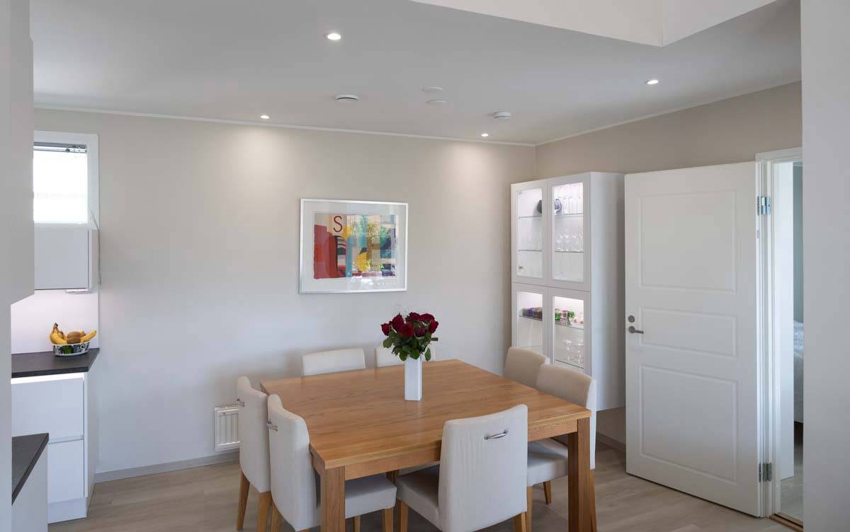 Lampes LED dans la salle à manger avec spots encastrés dans le plafond et dans la vitrine en verre également éclairée par des bandes LED.