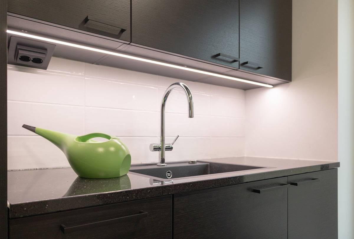 Sur le plan de travail de la buanderie, la surface sombre est éclairée par une bande LED dans un profilé d'aluminium noir. ©LedStore