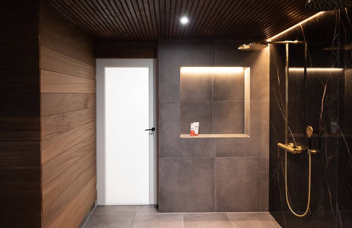 La bande LED dans la rainure du plafond et en haut de l'étagère à shampoing fournit un éclairage général doux dans la salle de bains. Spots supplémentaires de 9W, fixes et étanches. LedStore.fi  