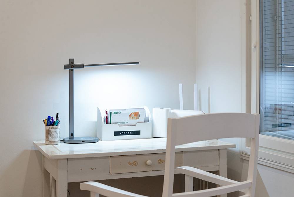 La lampe de table Crane de LedStore éclaire un poste de travail lumineux.