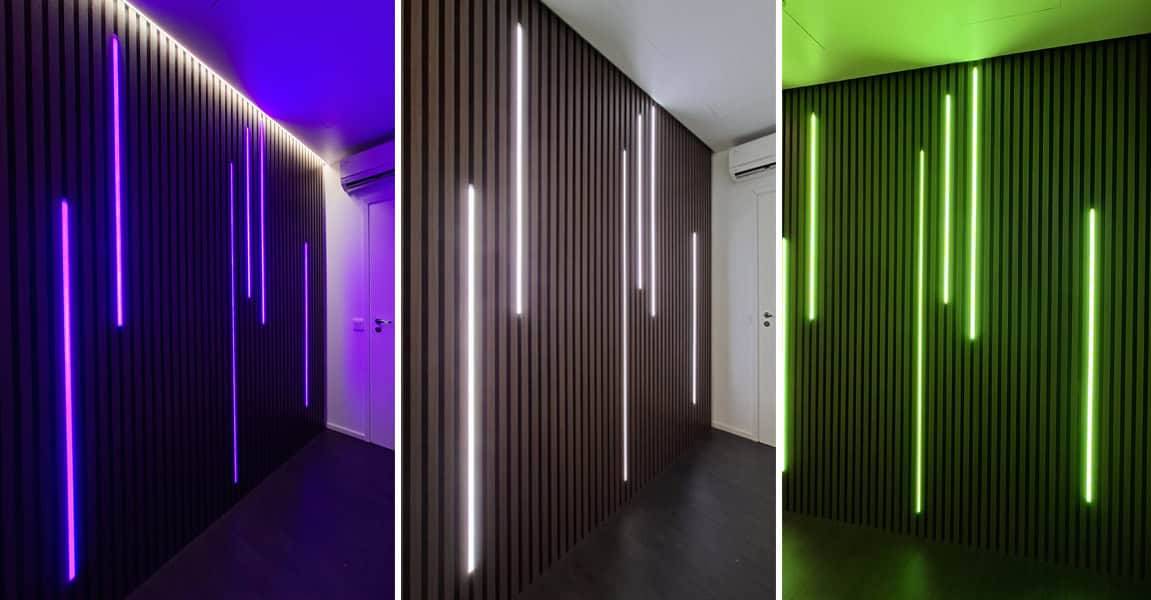 Un mur sombre élégamment lambrissé avec des LED LedStore.fi qui brillent en bleu, blanc et vert.