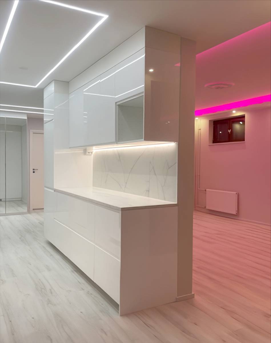 Ligne lumineuse carrée au plafond de la cuisine et lumière led rose dans le salon.